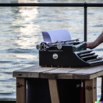 DALL·E 2022-07-03 23.42.04 - close up of a typewriter on a folding table being used by a londo...png